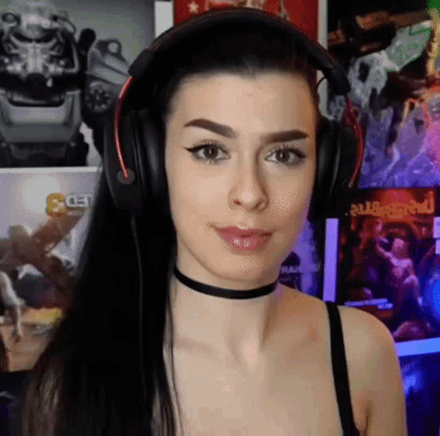 a woman wearing headphones and a choker looks at the camera while playing a video game .