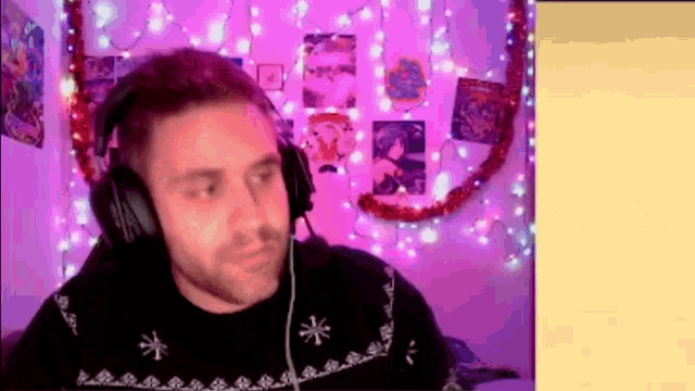a man wearing headphones and a sweater is sitting in front of a pink wall .