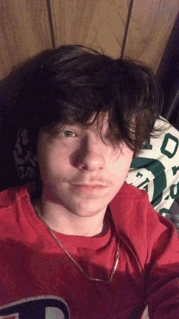 a young man is wearing a red shirt with the letter t on it