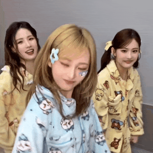 three girls are standing next to each other wearing pajamas with animals on them .