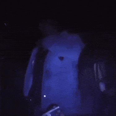a close up of a person 's face in a dark room with a blue light behind them .
