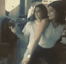 two women are dancing together in a room while taking a selfie .