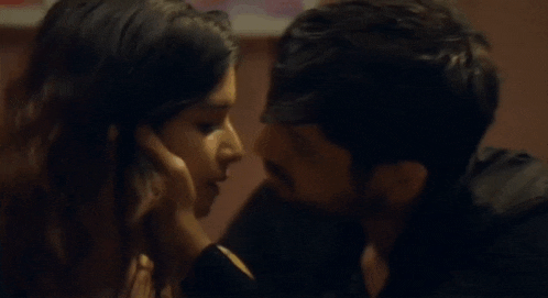 a man and a woman are kissing and touching each other 's faces .
