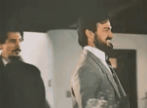 a man in a suit and tie is standing next to another man in a black suit .