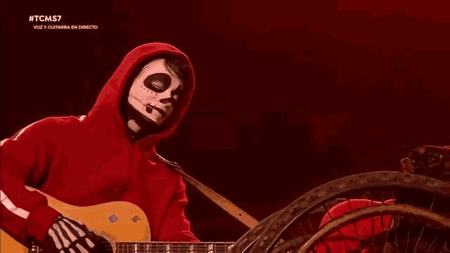 a man in a skeleton costume is playing a guitar on stage .