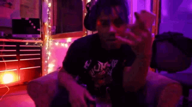 a man is sitting in a chair with purple lights behind him and wearing a shirt that says ' human '