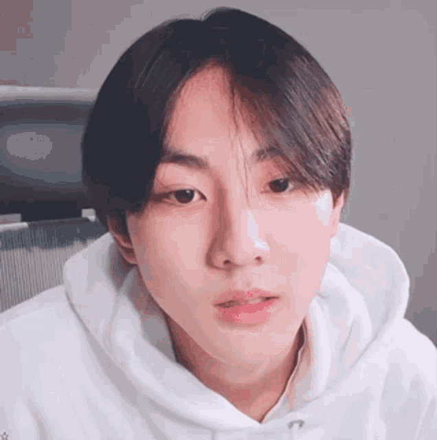 a young boy wearing a white hoodie is looking at the camera .