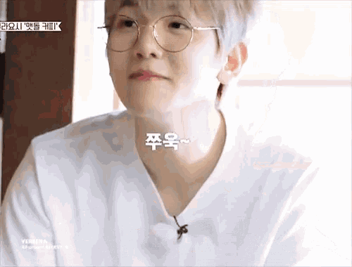 a close up of a person wearing glasses and a white shirt with korean writing on it