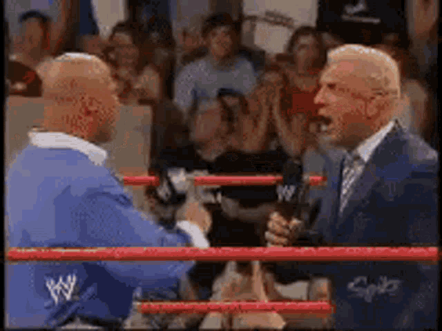 two men in a wrestling ring with one wearing a blue shirt that says ' w ' on it