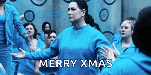 a woman in a blue sweater is standing in front of a group of women in blue sweatshirts .