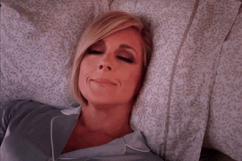 a woman is laying on a bed with a pillow and smiling