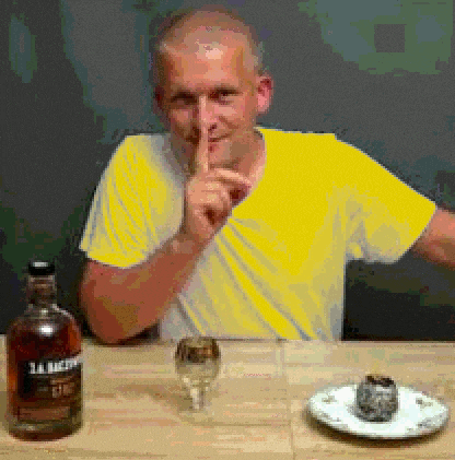 a man sitting at a table with a bottle of whiskey