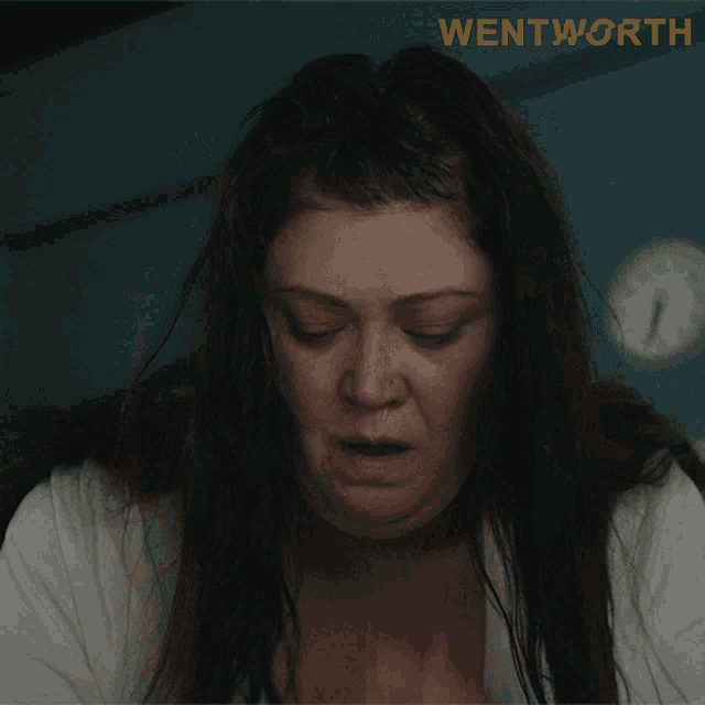 a woman covering her face with her hands in front of a sign that says " wentworth "