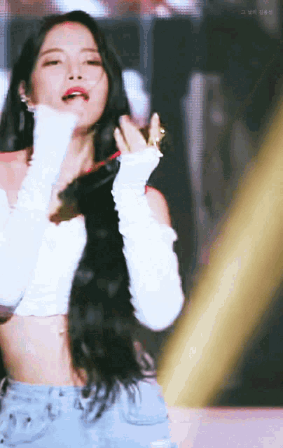 a woman with long black hair is wearing a white crop top and jeans