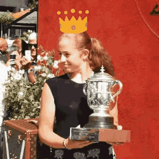 a woman wearing a crown holds a trophy