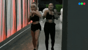 a couple of women walking down a hallway holding glasses of champagne