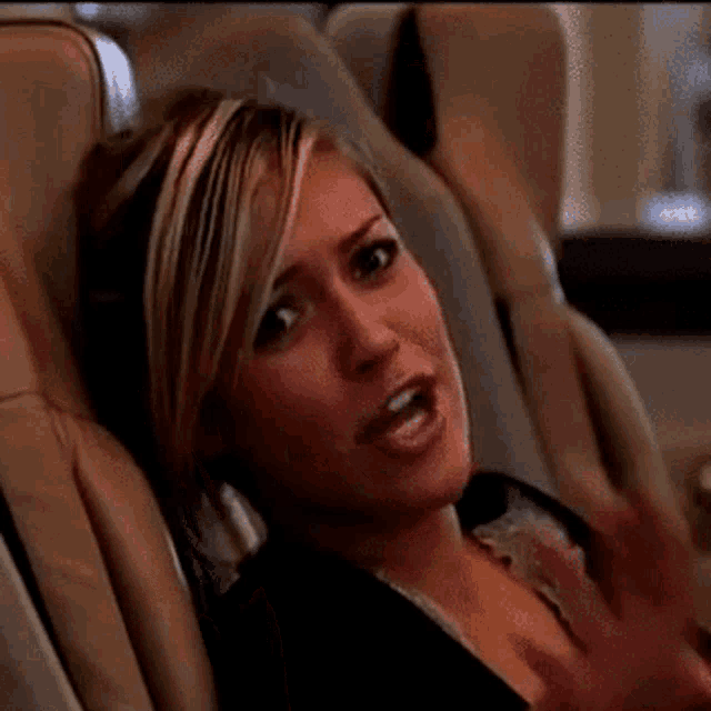 a woman is laughing while sitting in a chair with her hands up
