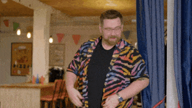 a man wearing a zebra print shirt is standing in front of a pizza sign
