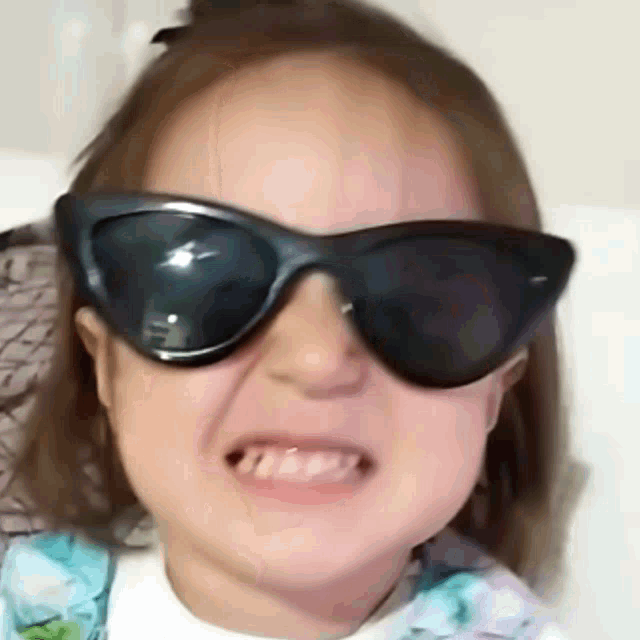 a little girl is wearing sunglasses and making a funny face
