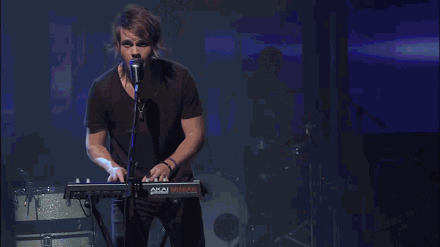 a man singing into a microphone while playing keyboards