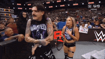 a man wearing a shirt that says wanted is standing next to a woman