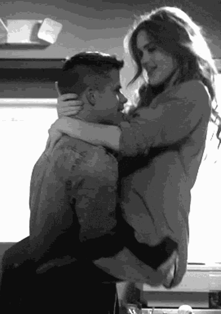 a black and white photo of a man and woman hugging each other