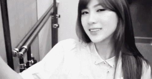 a black and white photo of a woman in a white shirt smiling .