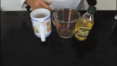 a bottle of olive oil sits next to a measuring cup and a mug