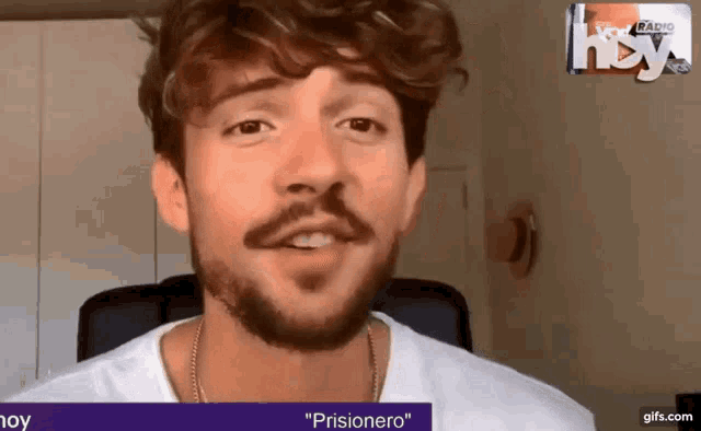a man with a beard and mustache is sitting in front of a screen that says " prisionero "