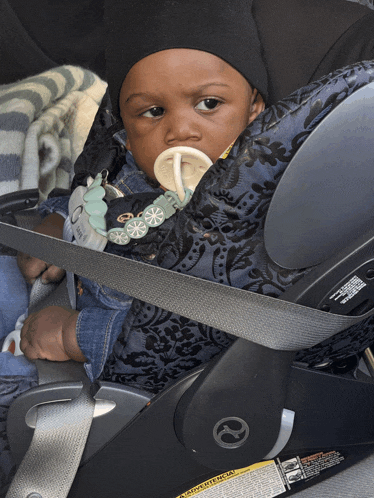 a baby wearing a pacifier is sitting in a car seat
