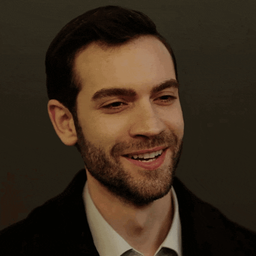 a man with a beard wearing a white shirt and a black jacket