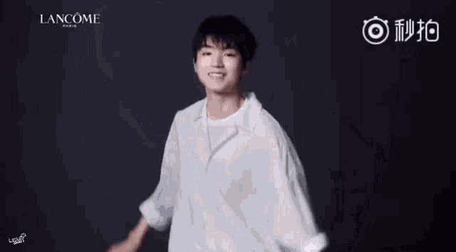 a man in a white shirt is dancing in front of a lancome ad