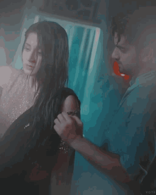 a man brushes a woman 's hair with a red toothbrush in a blurry photo