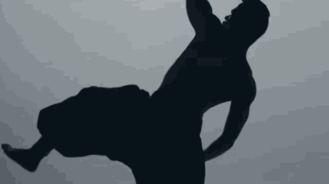 a silhouette of a man without a shirt is doing a handstand