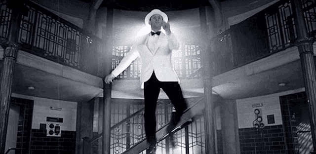 a man in a tuxedo is standing on a set of stairs in a building .