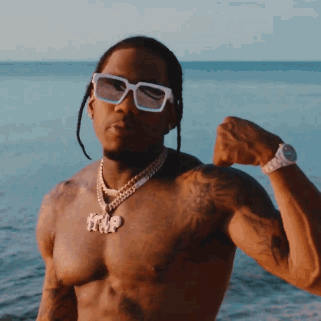 a shirtless man wearing sunglasses and a necklace that says trip on it
