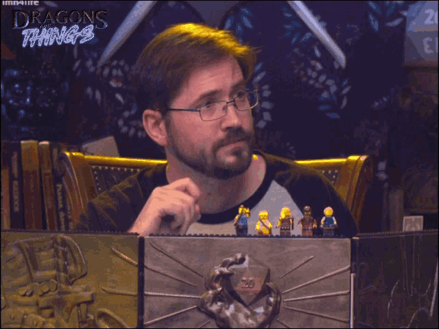 a man with glasses sits in front of a table with okay on it
