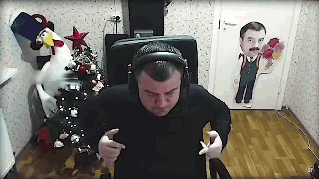 a man wearing headphones stands in front of a christmas tree and a door with a picture of a man on it