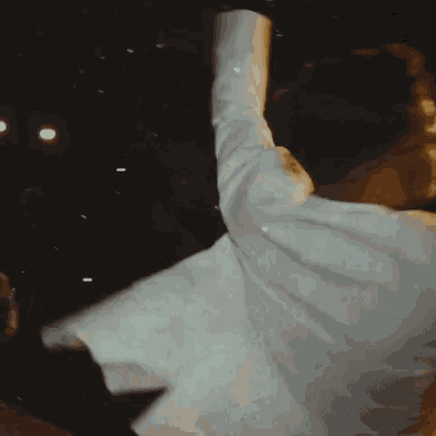 a man in a white suit and glasses is dancing in a dark room