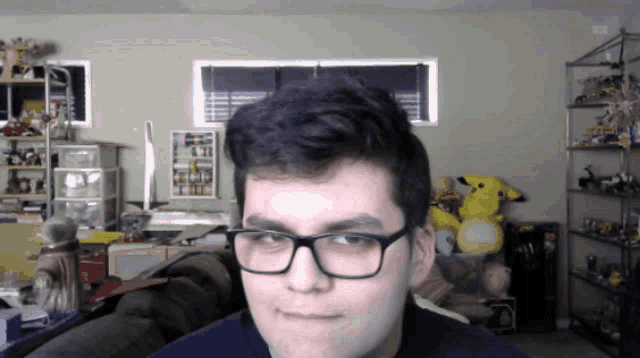 a young man wearing glasses looks at the camera in a room full of toys