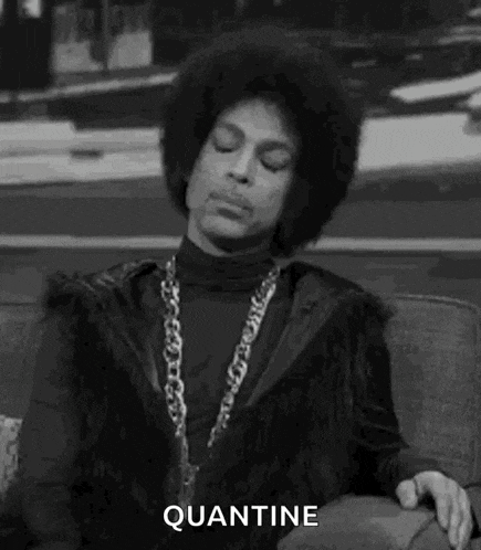 prince is sitting on a couch with his eyes closed and wearing a fur coat and a chain around his neck .