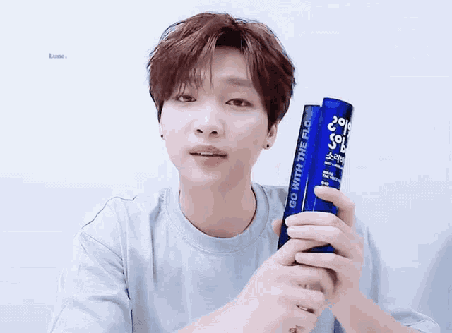 a young man is holding a blue bottle that says go with the flow