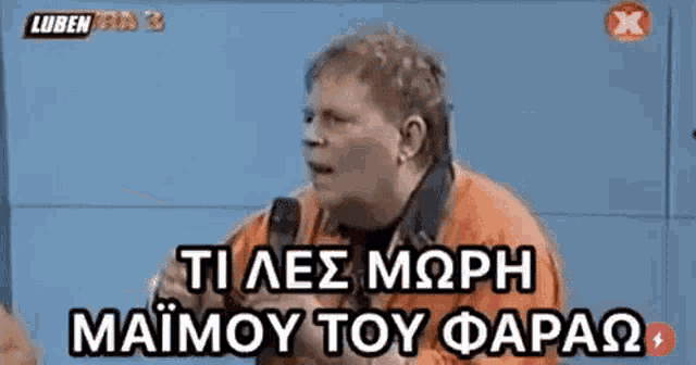 a man in an orange shirt is talking into a microphone in greek