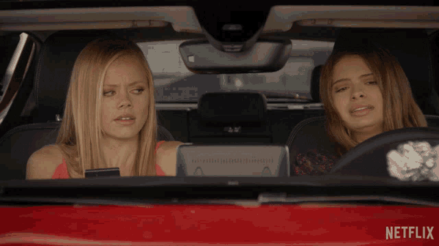 two women are sitting in a red car with a netflix logo on the side