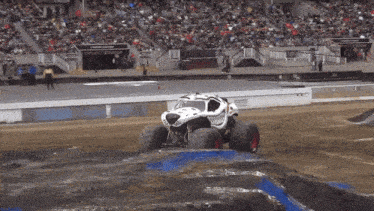 a monster truck with a skull on the side is driving down a dirt track