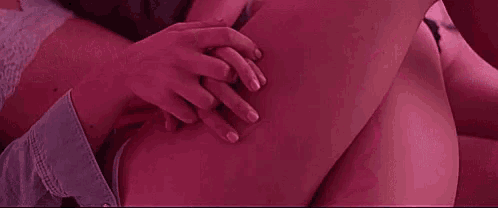 two women are laying next to each other on a bed with pink lights .