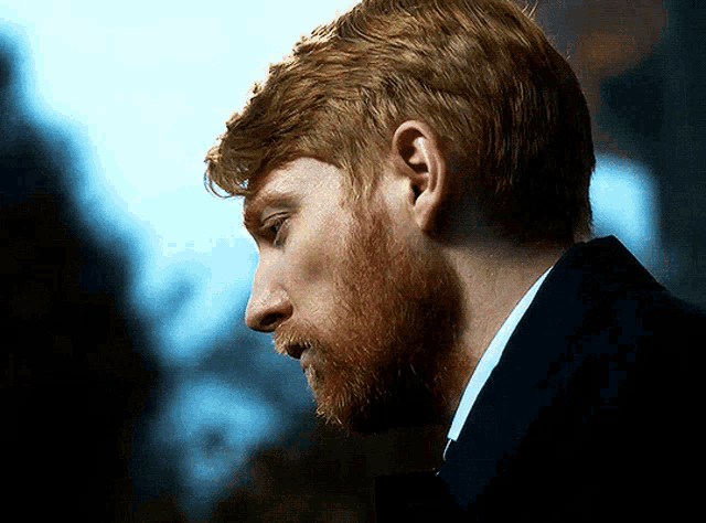 a man with red hair and a beard looks down