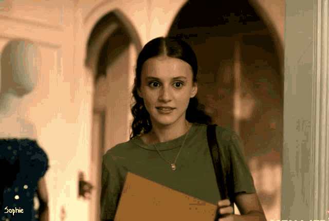 a woman in a green shirt is holding a folder and the word sophie is on the bottom