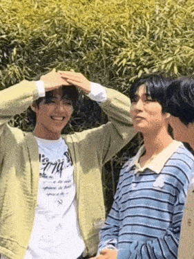 a group of young men are standing next to each other and one of them is making a heart with his hands .
