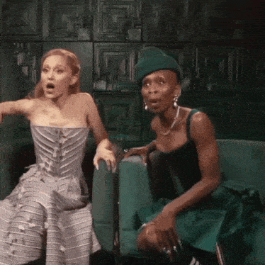two women are sitting next to each other on a green couch